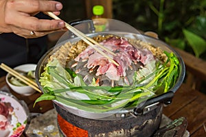 Pork on a hot plate or Mookata.The â€œMoo Kataâ€ literally â€œpork panâ€,an aluminum dome grill is placed on a small clay fire