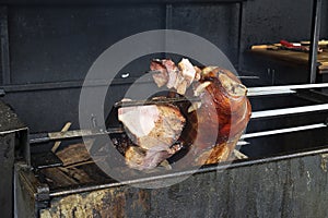 Pork knuckle is fried on a spit. Street grill, fried meat with crispy brown crust. Street food, pieces of meat. Traditional food