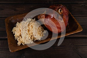 Pork knuckle with sauerkraut on a wooden plate. Oktoberfest. rustic