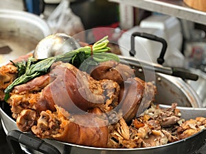 Pork knuckle stewed in pot at street food market.