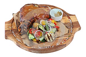 Pork knuckle with vegetable salad on round wooden board, isolate