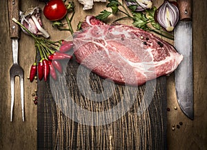 Pork meat chops with fresh herbs and spices for cooking, fork and knife on rustic wooden background, top view