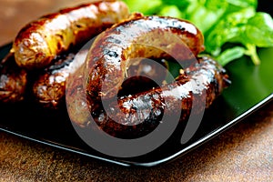 Pork meat sausages on a black plate