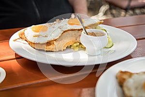 Pork meat Schnitzel Hamburg style with fried eggs, potato cucumber salad and Bavarian sweet mustard in Biergarten restaurant photo