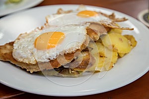 Pork meat Schnitzel Hamburg style with fried eggs and roast potatoes in Biergarten restaurant photo