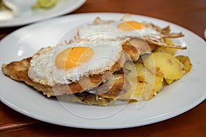 Pork meat Schnitzel Hamburg style with fried eggs and roast potatoes in Biergarten restaurant photo