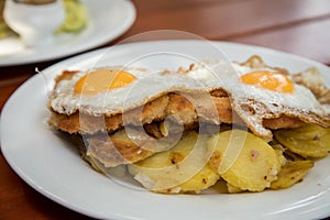 Pork meat Schnitzel Hamburg style with fried eggs and roast potatoes in Biergarten restaurant photo