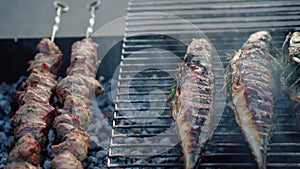 Pork meat shashlik and scomber fish cooking on barbeque grill. Smoke rising