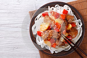 Pork meat in sweet and sour sauce with rice noodles top view