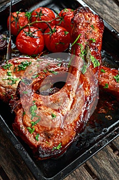 Pork middle chop roast with sweet and sour souce, baked tomatoes and red onion