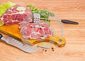 Pork neck on cutting board, spices, meat tenderizer and knife