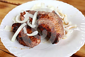 Pork neck kebabs with onions on white plate