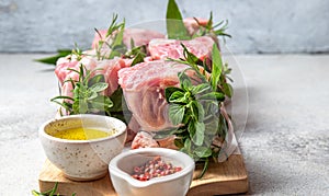 Pork Osso Buco, shin Pork shanks with fresh aromatic herbs on white marmol board