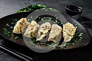 Pork Potstickers on rustic black table. Dim sum on a plate. Top view