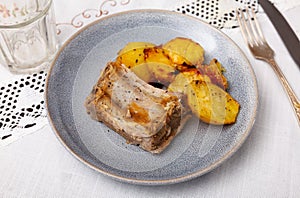 Pork ribs with boiled potatoes and spices on ceramic plate photo