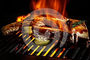 Pork ribs over flaming grill grid, on black background. Barbecue and cooking. baby ribs with barbecue sauce. American cuisine,