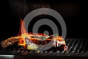 Pork ribs over flaming grill grid, on black background. Barbecue and cooking. baby ribs with barbecue sauce. American cuisine,