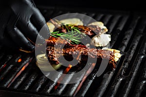 Pork ribs over flaming grill grid, on black background. Barbecue and cooking. baby ribs with barbecue sauce. American cuisine,