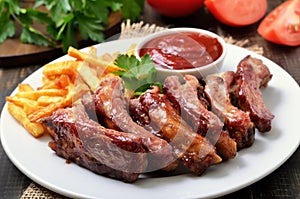 Pork ribs, potato fries and tomato sauce, close up view