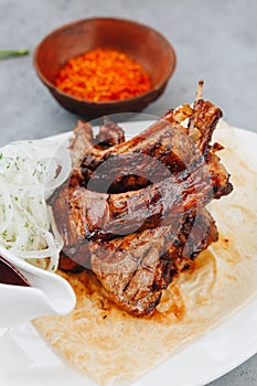 Pork ribs and tomato sauce on white plate. Close up view