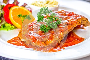 Pork ribs, vegetables and spaghetti in a white dish topped with sauce