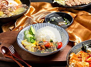 Pork Rice with tomato, cucumber, fork and spoon served in dish isolated on wooden board side view of asian food