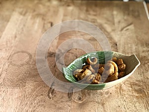 pork rind snack in green plate on wooden table background.