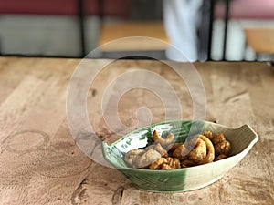 pork rind snack in green plate on wooden table background.