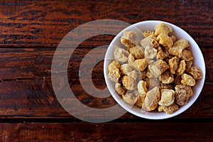 Pork rinds fried in ceramic bowl on rustic wooden table in restaurant