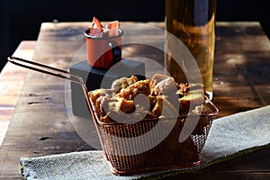 pork rinds fried in ceramic bowl on rustic wooden table in restaurant. typical dish of Brazilian and Asian cuisine