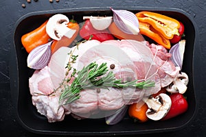 Pork roll with vegetables in a baking sheet before baking. Meat with sweet pepper, mushrooms, purple onions with spices