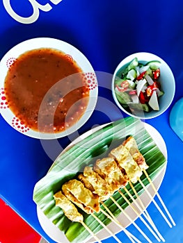 Pork satay served on a blue table.