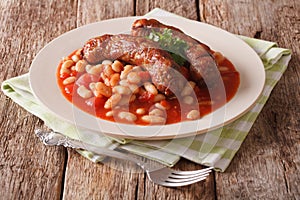 Pork sausages with beans and cooked tomatoes on a plate close-up