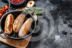 Pork sausages in a cast-iron pan. Black background. Top view. Copy space