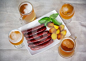 Pork sausages, glasses of beer, roasted potatoes. Selective focus