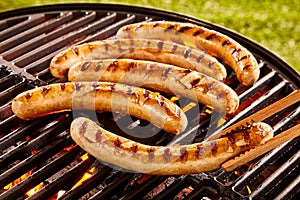 Pork sausages grilling on a portable BBQ