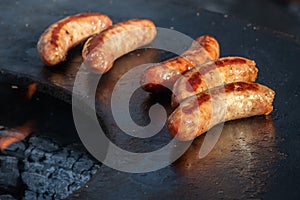 Pork sausages ready to eat, grilled or roasted in a barbecue on an open fire and flames