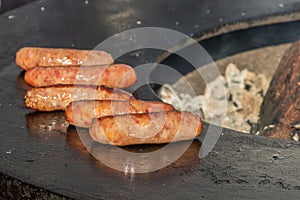 Pork sausages ready to eat, grilled or roasted in a barbecue on an open fire and flames