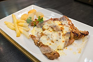 Pork steak with cheese served with french fries and hash brown p