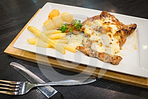 Pork steak with cheese served with french fries and hash brown p