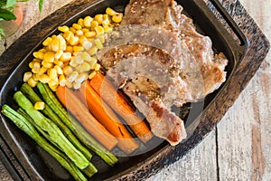 Pork steak with vegetable. Corn, carrots, green beans, on wooden