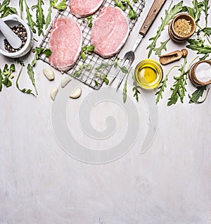 Pork steaks on the grill for roasting with meat fork, butter, rosemary and arugula border ,place text on wooden rustic backgr