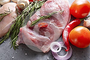 Pork tenderloin with rosemary, onions, chili peppers and tomatoes, raw meat with vegetables and herbs