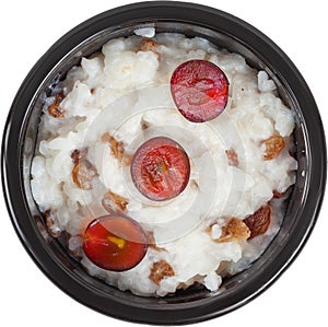 Porridge in disposable round plastic black bowl top view on white background