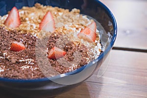 Porridge - healthy breakfast for children and adults. Breakfast cereal with strawberries and chocolate for breakfast in a blue cup