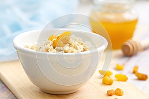 Porridge with raisin and honey in white bowl for breakfast