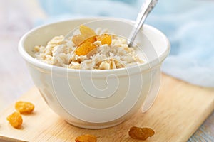 Porridge with raisin and honey in white bowl for breakfast