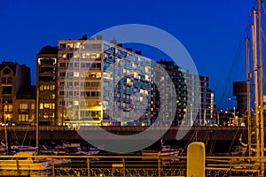 The port of Blankenberge with lighted buildings at night, city architecture and scenery of a popular town in Belgium