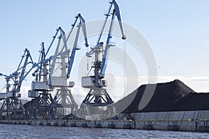 The Port blue cranes load coal into vagon. The territory of the coal port near the river