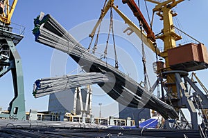 Port crane loads building reinforcement onto a ship